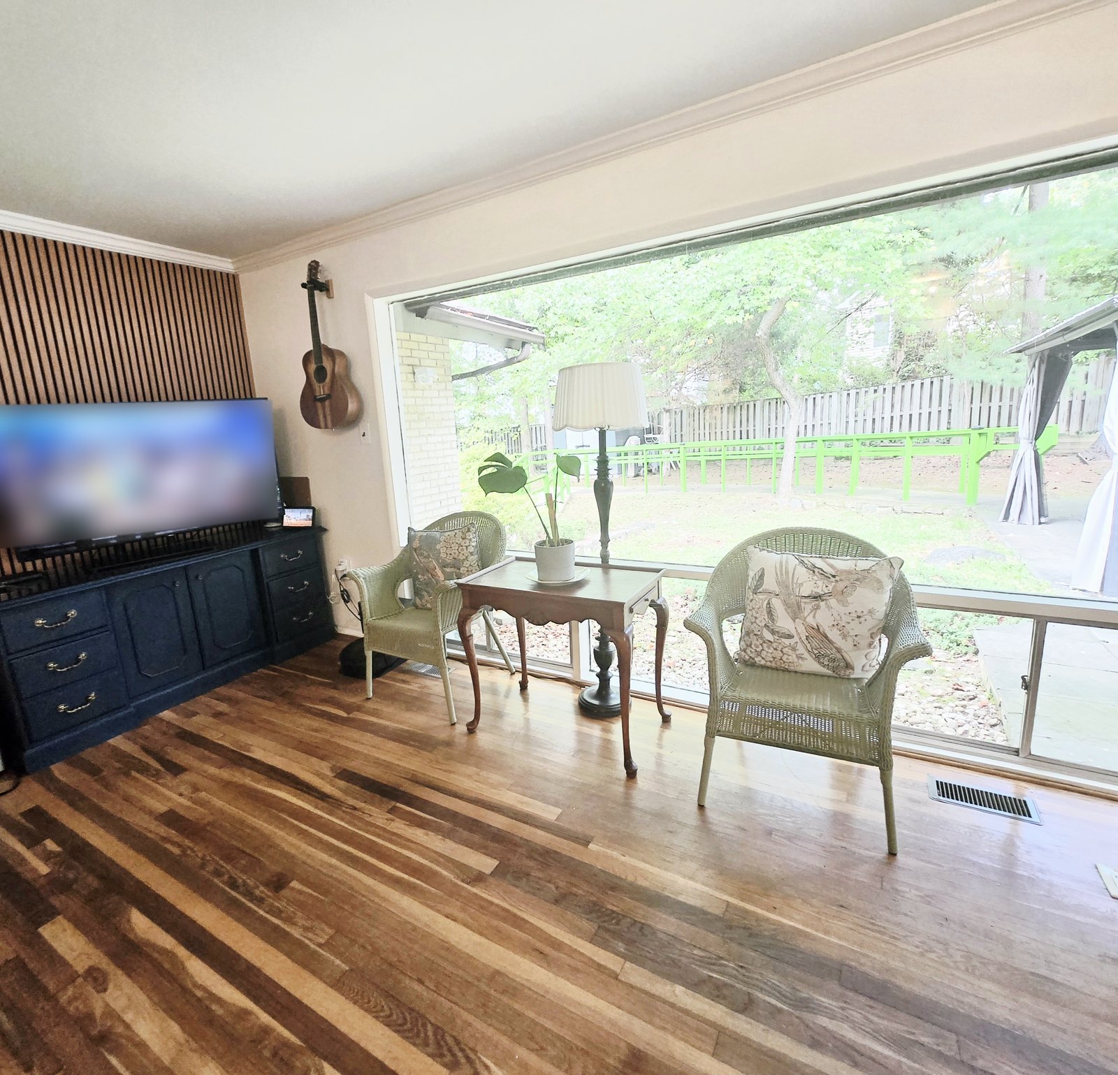 Living room with a wide picture window onto the garden and two wicker chairs
