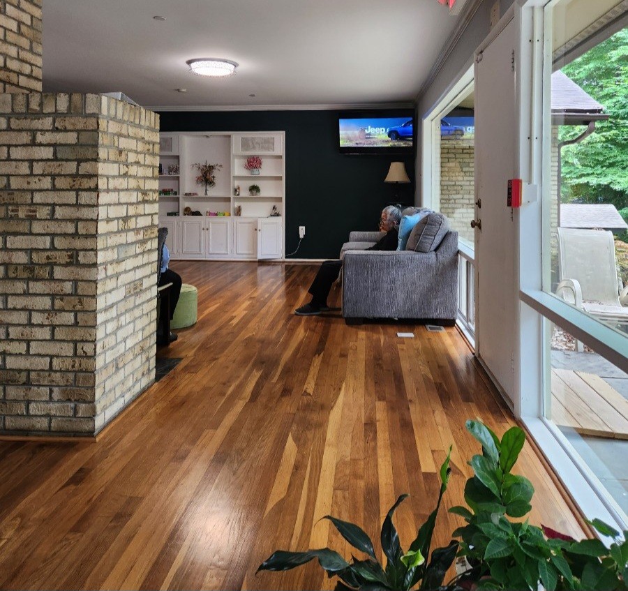 Bright common room with hardwood floors and garden views