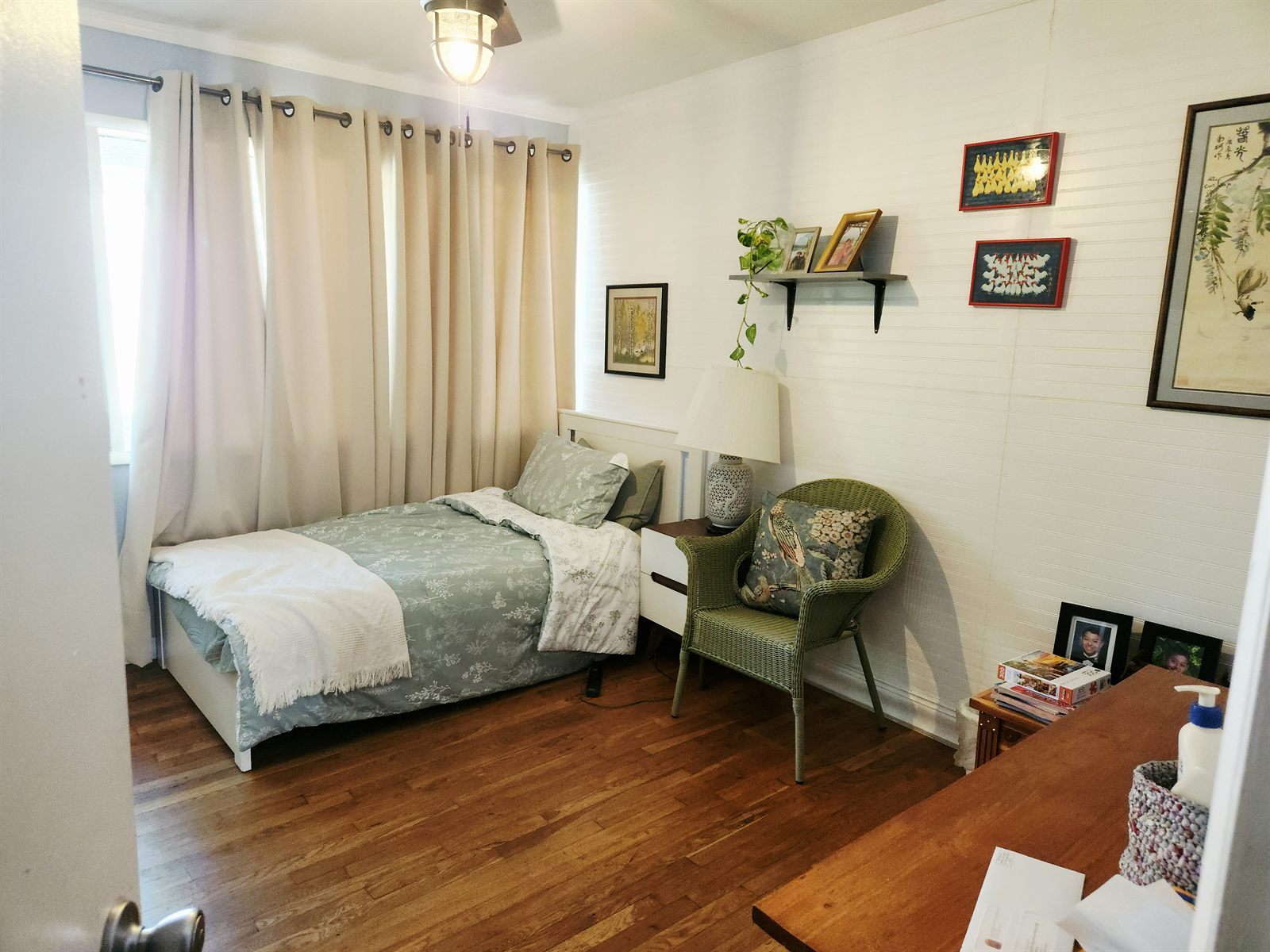 Private Room 1 with floral bedding, personal artwork, and large curtained windows